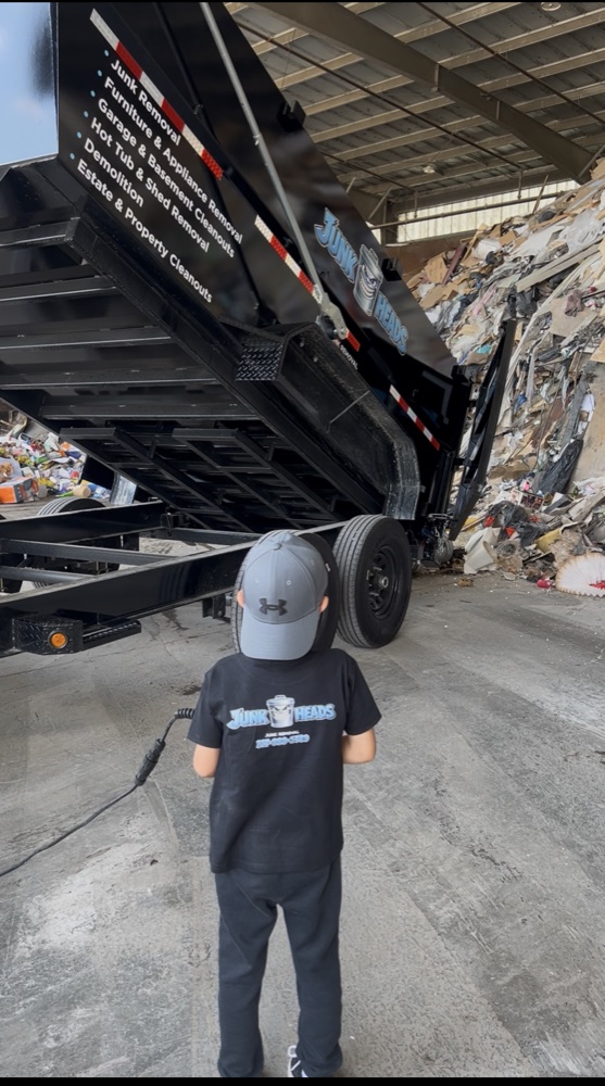 A child in a Junk Heads t-shirt watching the dump trailer unload at the recycling transfer station